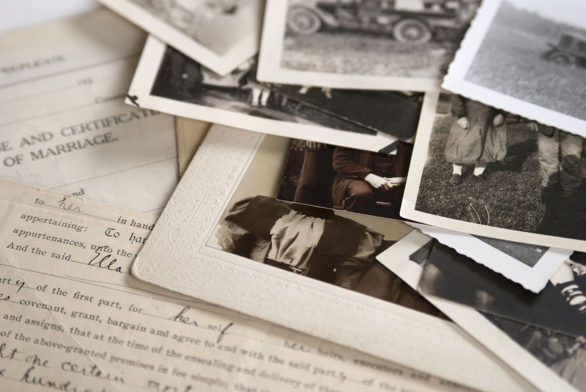 Scattered black-and-white vintage photos and handwritten papers on a tabletop