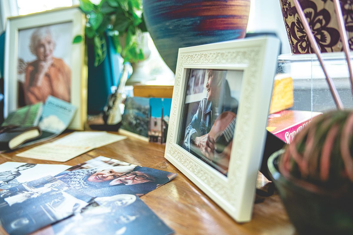 Framed photos and colorful decor arranged on a wooden table near a sunlit window