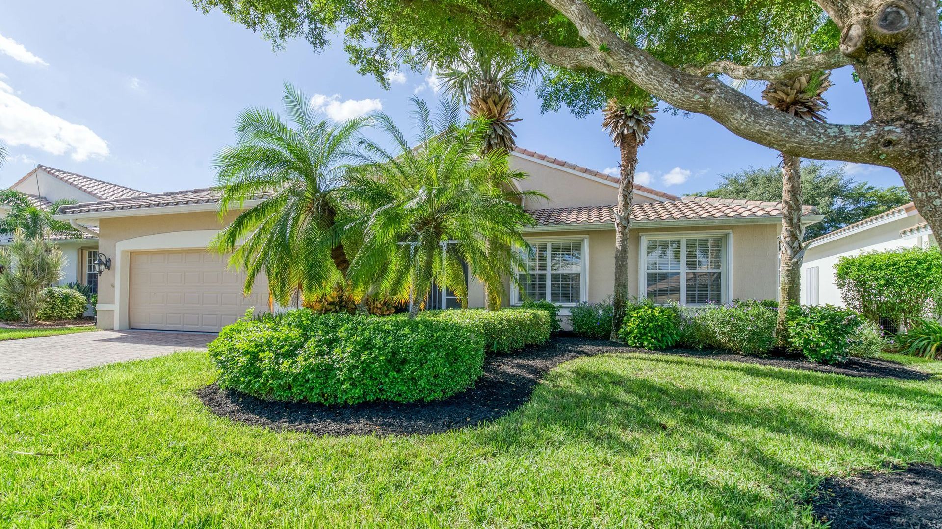 A house with a lush green lawn and palm trees in front of it.