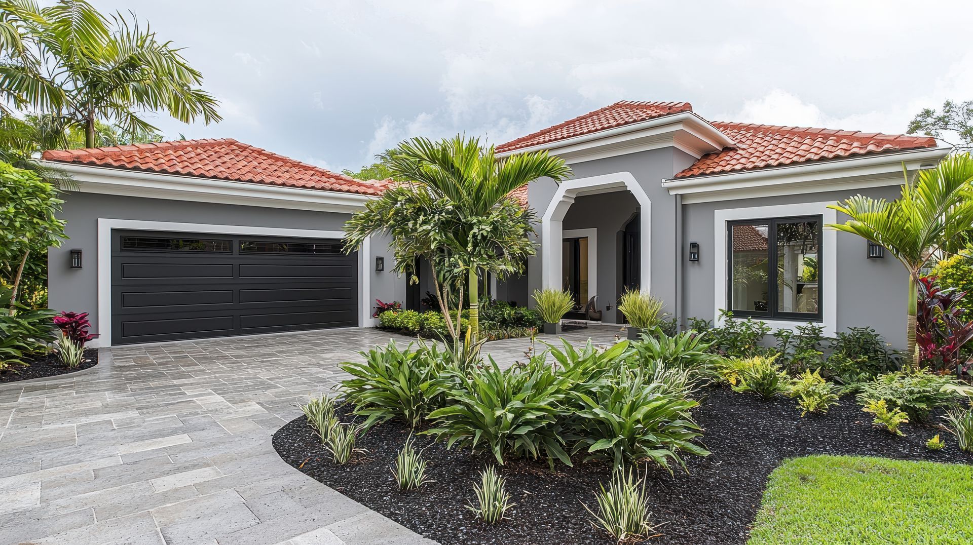 A large house with a black garage door and a red tile roof