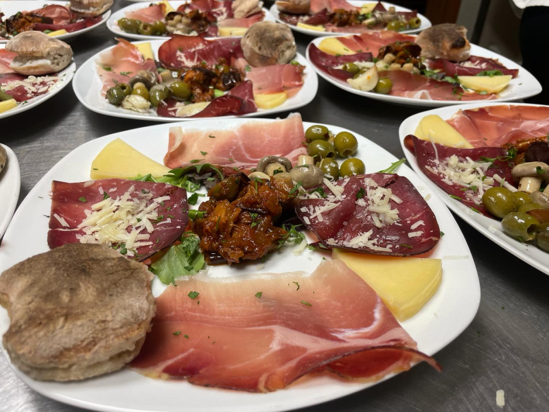 Piatti di antipasti italiani assortiti con prosciutto, formaggio, olive e pane su un tavolo