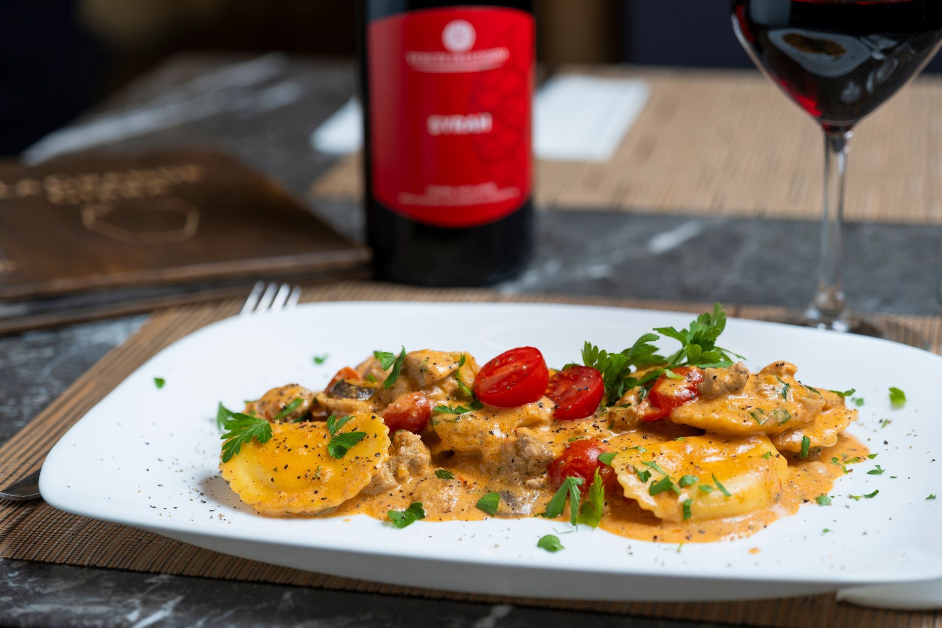 Ravioli ricoperti di formaggio in salsa verde cremosa, serviti su un piatto bianco e guarniti con erbe aromatiche tritate.