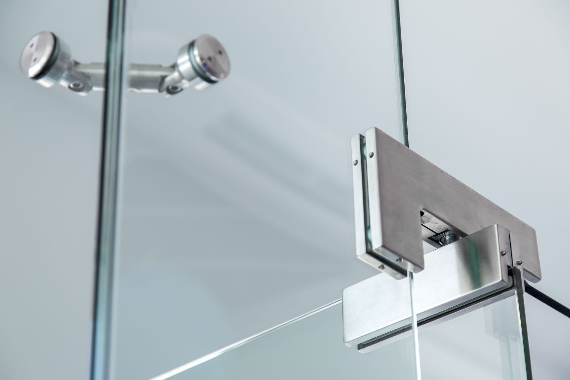 Un gros plan d'une porte en verre avec une charnière en acier inoxydable.