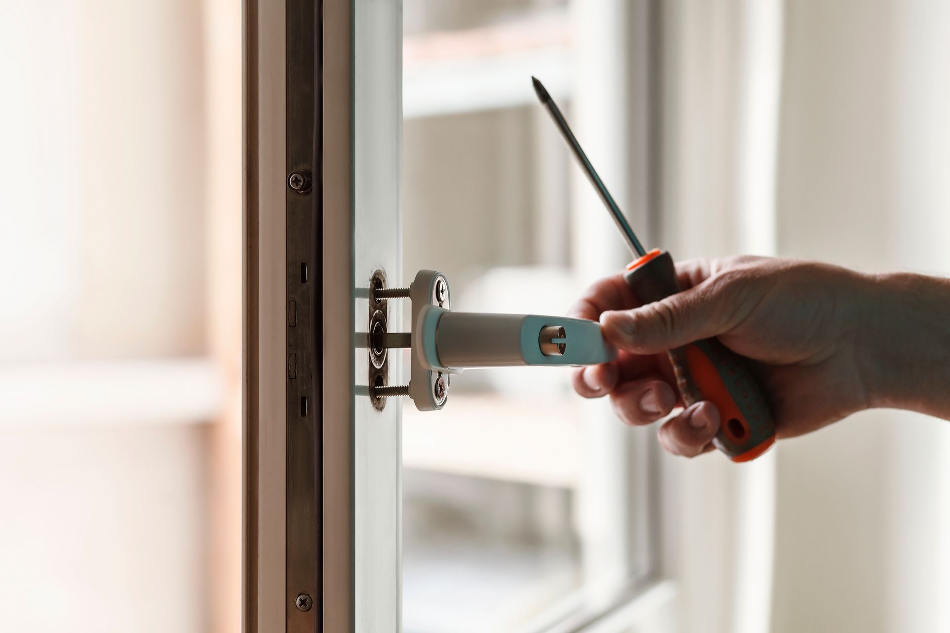 Une personne répare une poignée de porte avec un tournevis.