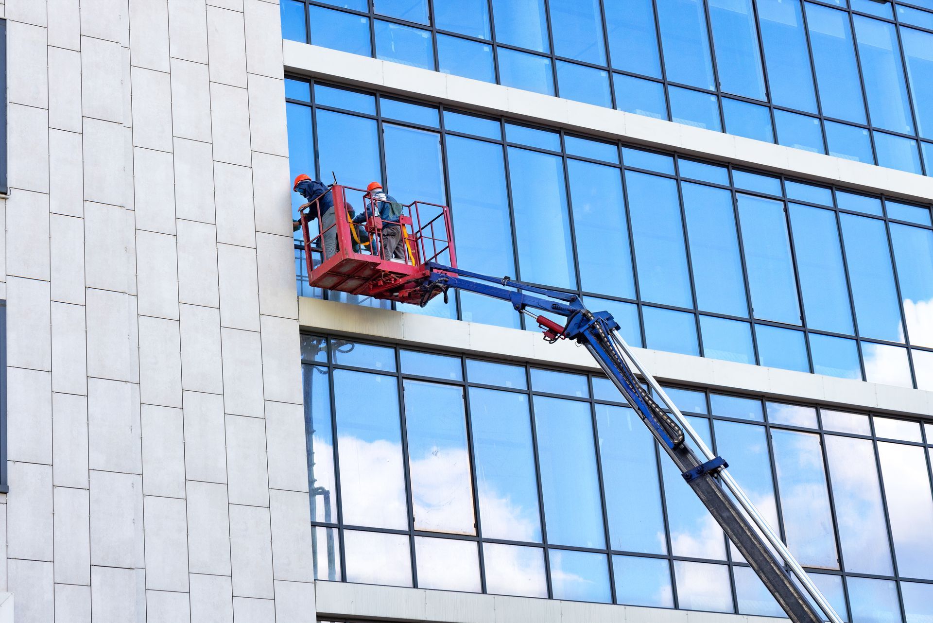 Une grue nettoie les fenêtres d'un grand immeuble.