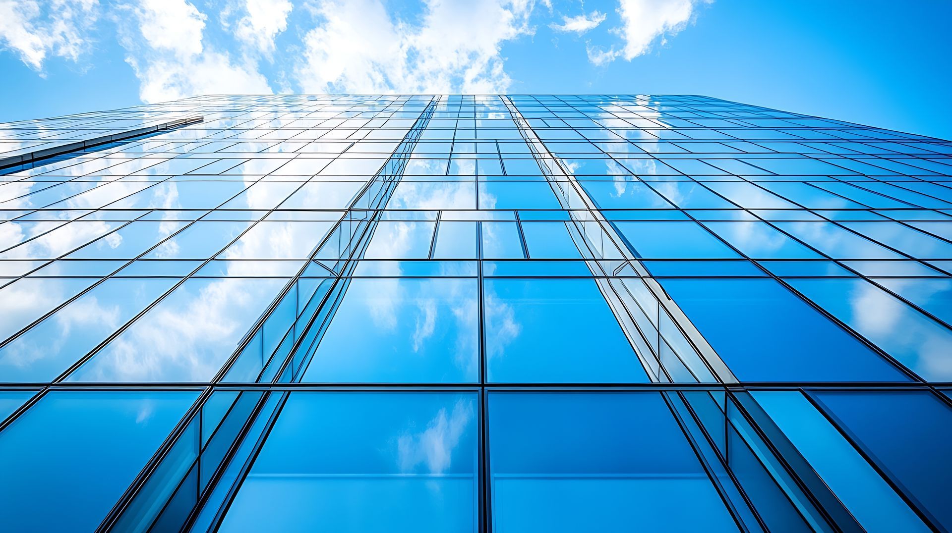 Regardant un grand bâtiment avec un ciel bleu et des nuages reflétés dans les fenêtres.