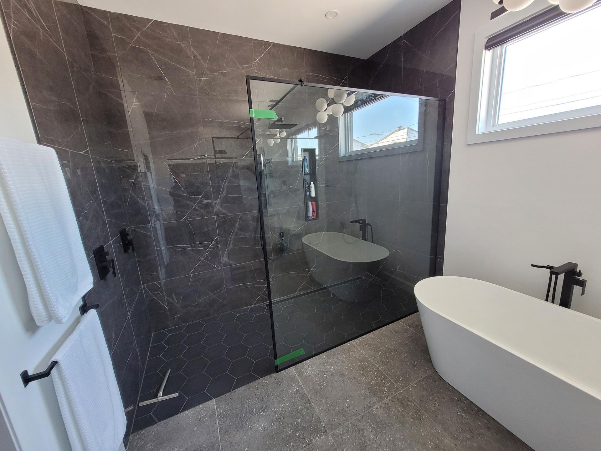 Une salle de bain avec douche à l'italienne, baignoire, lavabo et fenêtre.