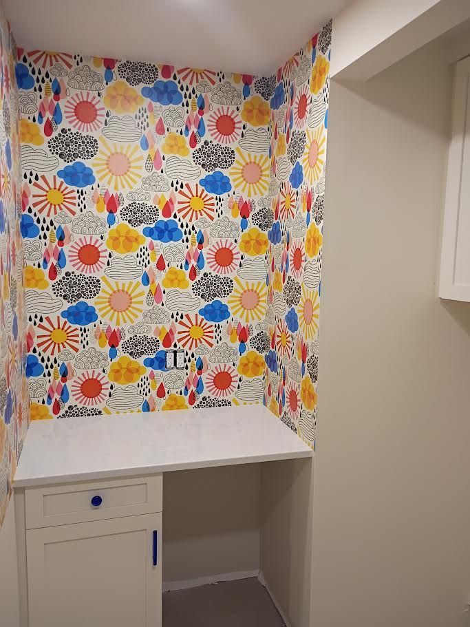 Small alcove with colorful patterned wallpaper, white countertop, and built-in cabinet.