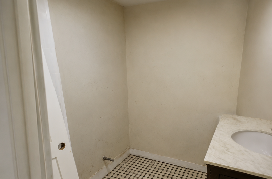 Empty beige bathroom with a tiled floor and countertop sink, viewed from the doorway