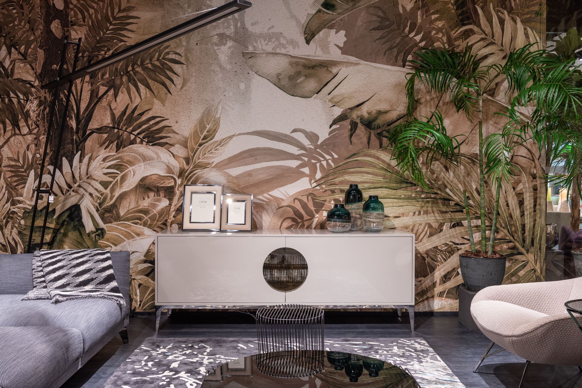 Stylish living room with tropical mural wall, white console, patterned sofas, and reflective black coffee table