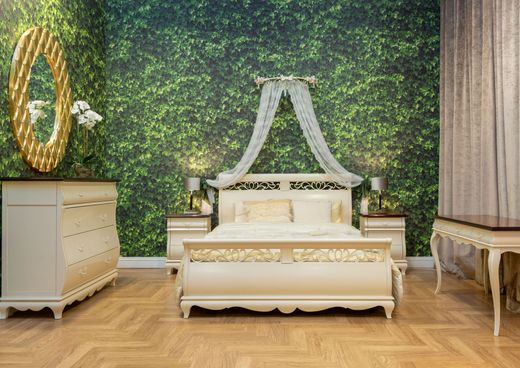 Elegant bedroom with a white canopy bed against a green leafy wall, flanked by matching bedside tables.