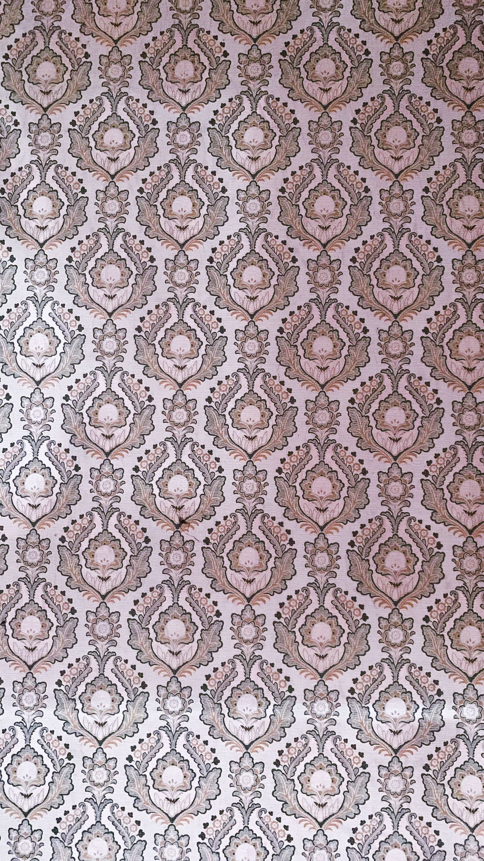 Pink and beige damask wallpaper pattern with a lighter section at the bottom