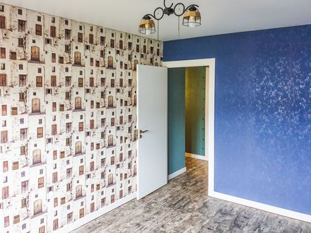Empty room with blue and patterned walls, an open door, and a ceiling light fixture