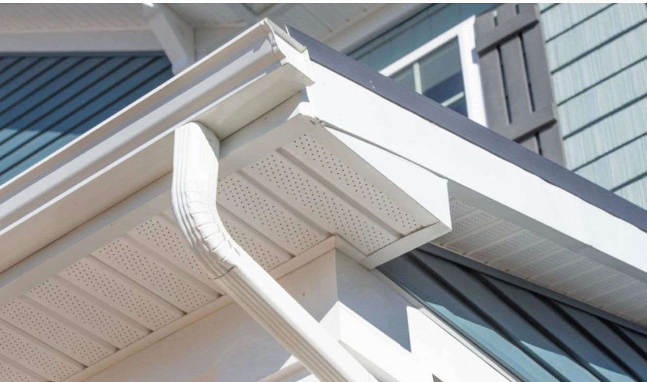 Close-up of white house eaves and guttering against blue-gray siding.
