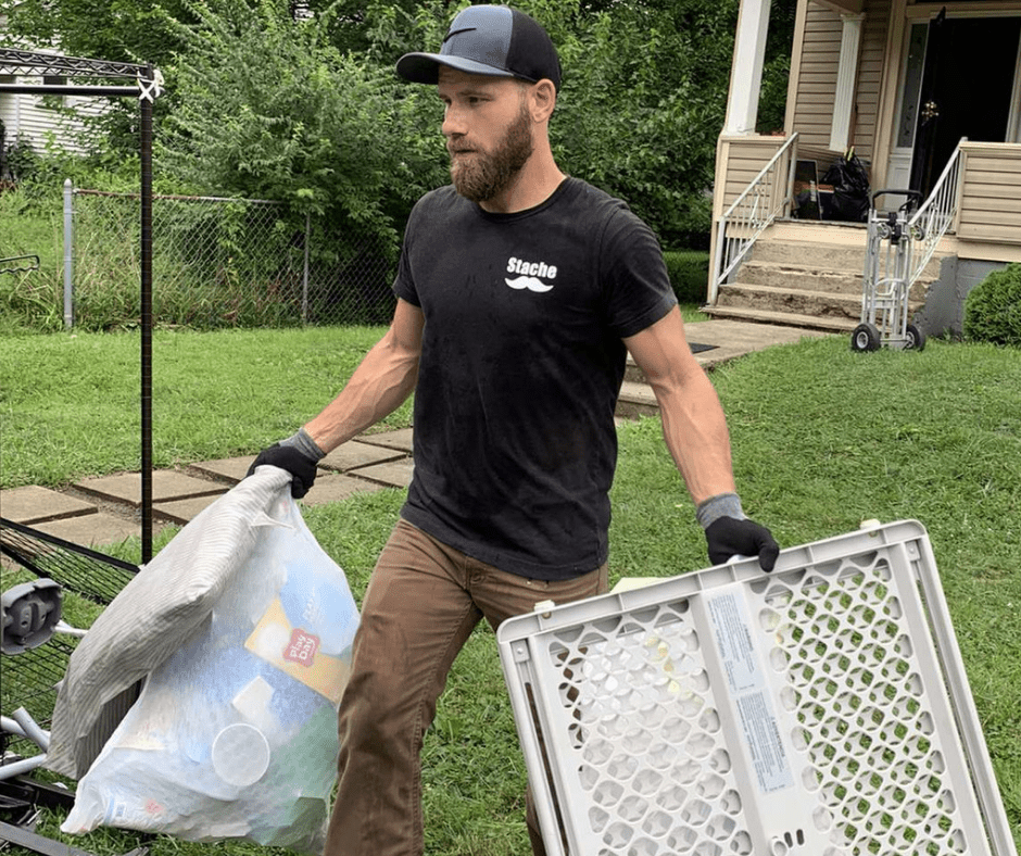 Stache crew member carrying a garbage bag and baby gate, hoarding cleanouts in Central OH