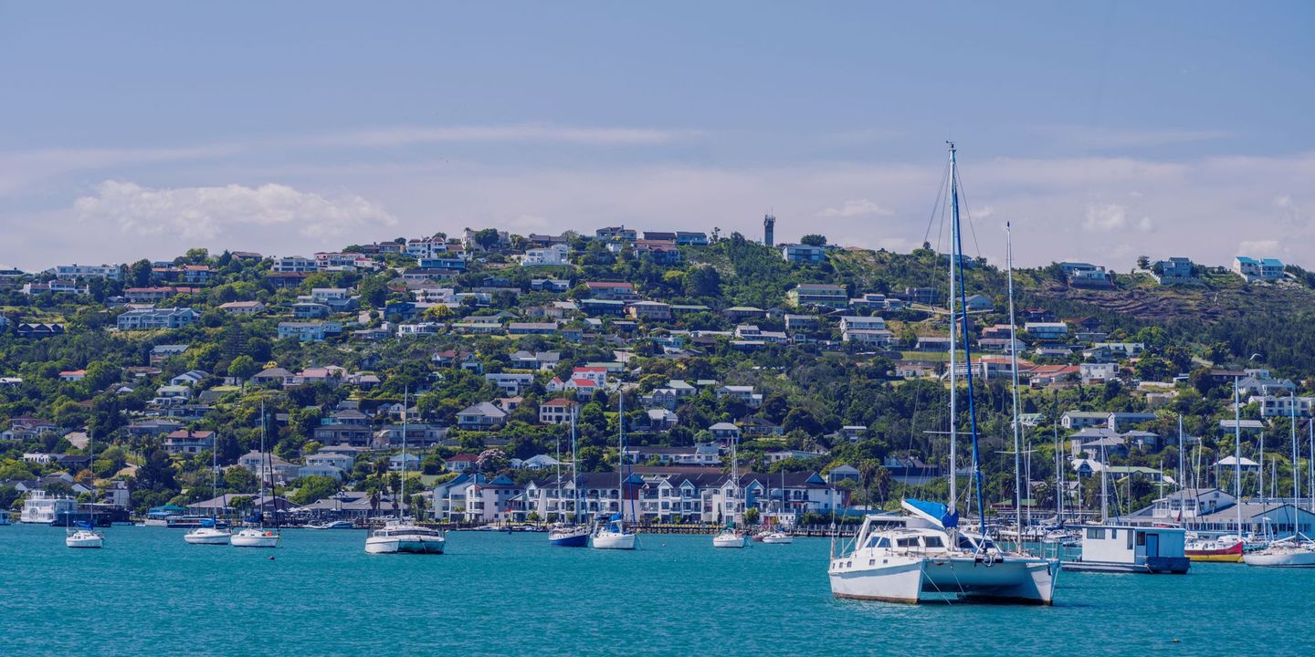 A group of boats are docked in a harbor with a city in the background.