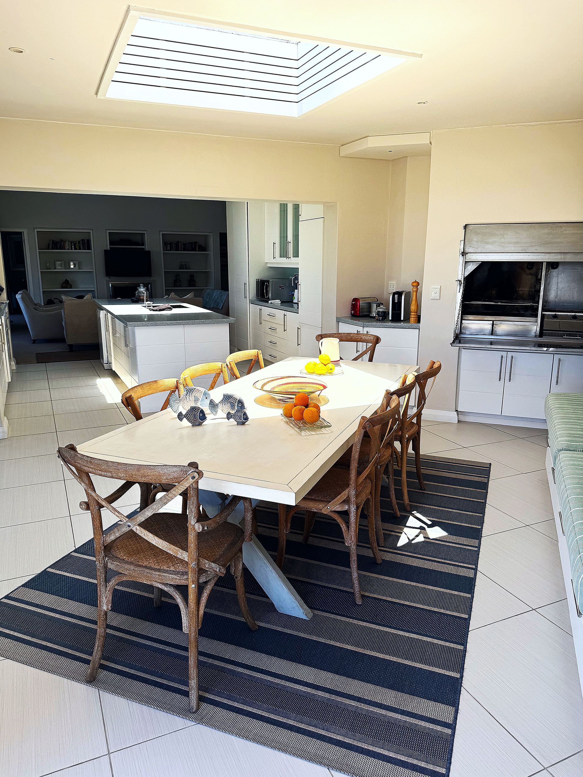 A dining room with a table and chairs and a rug on the floor.
