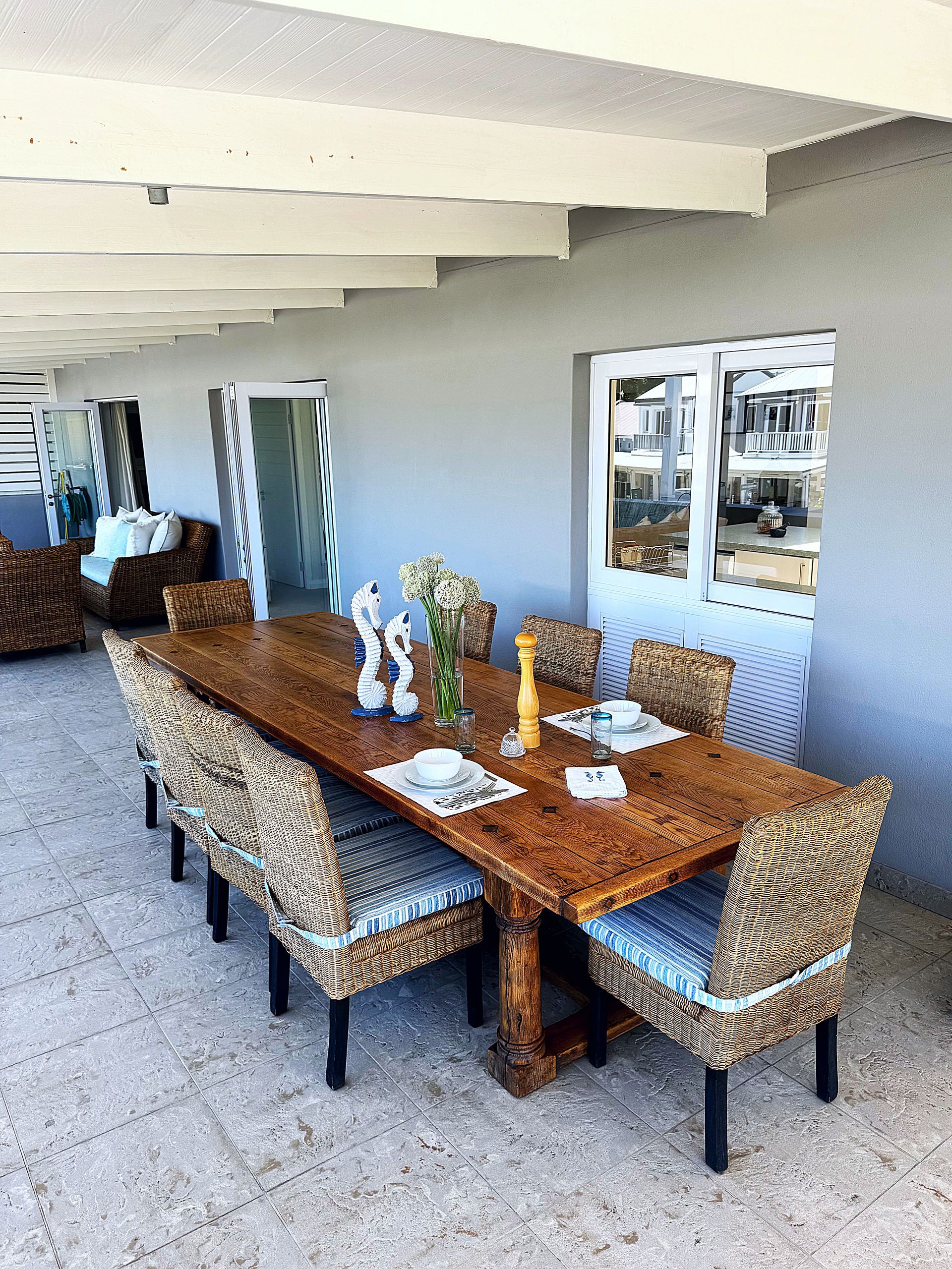 A dining room table with chairs and a vase of flowers on it.