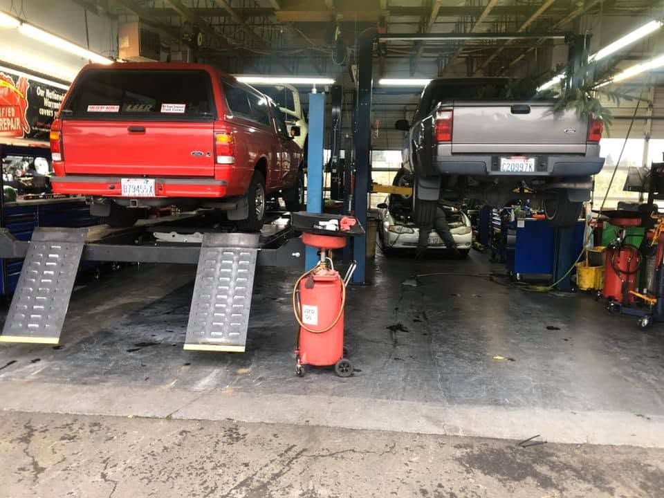 Two vehicles on ramps in a garage, with a red SUV on the left and a gray truck on the right | TrueTech Automotive