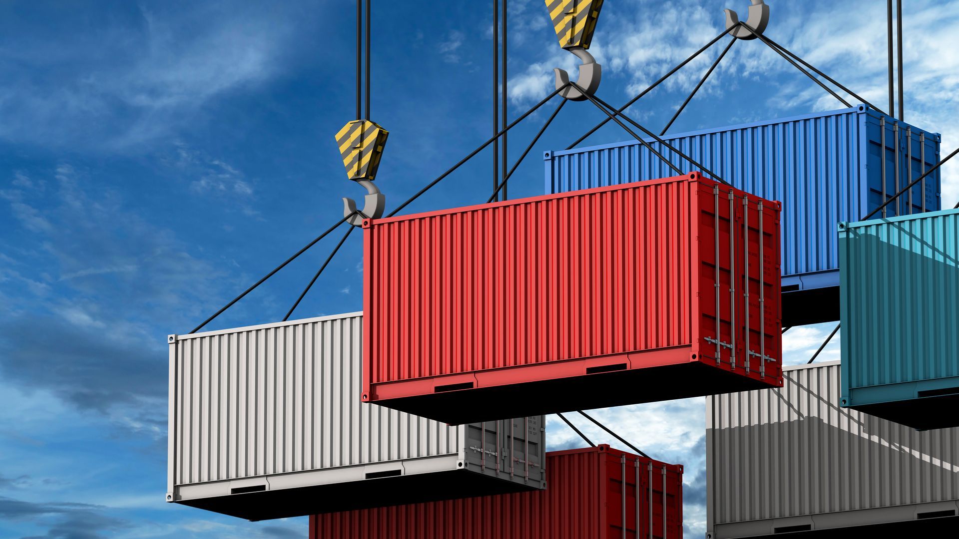 Shipping containers being lifted by a crane against a blue, cloudy sky. Shipping containers being lifted by a crane against a blue, cloudy sky.