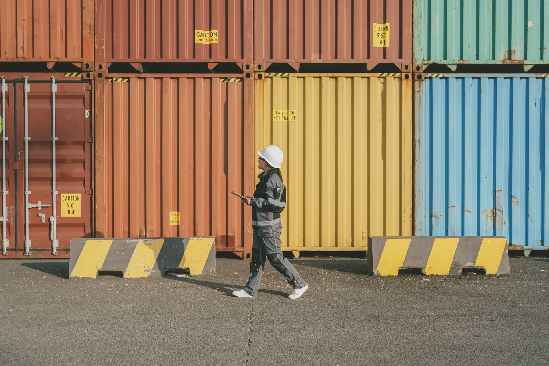 Worker in safety vest with stacked shipping containers, representing a shipping container supplier. Worker in safety vest with stacked shipping containers, representing a shipping container supplier.