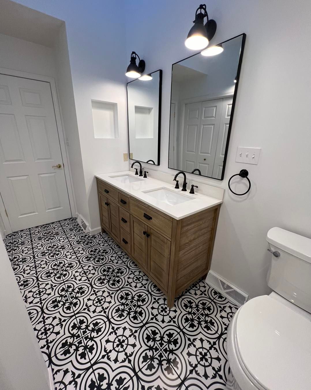 A bathroom with two sinks , two mirrors and a toilet.