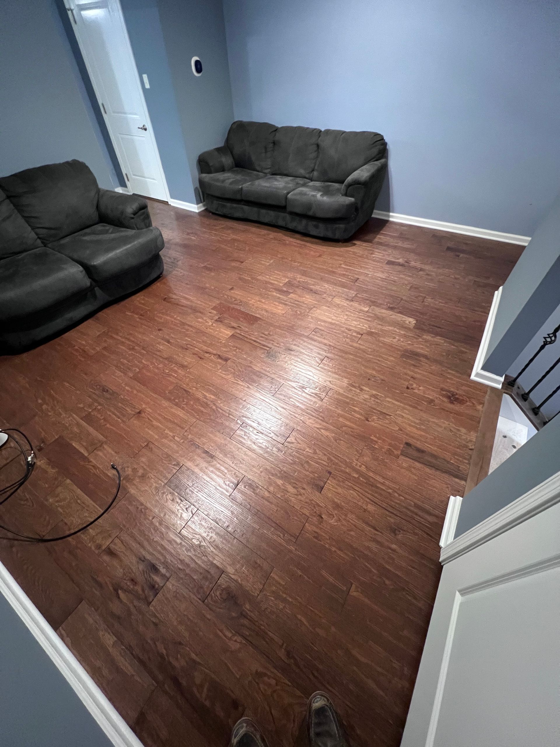 A living room with hardwood floors , a couch and a chair.