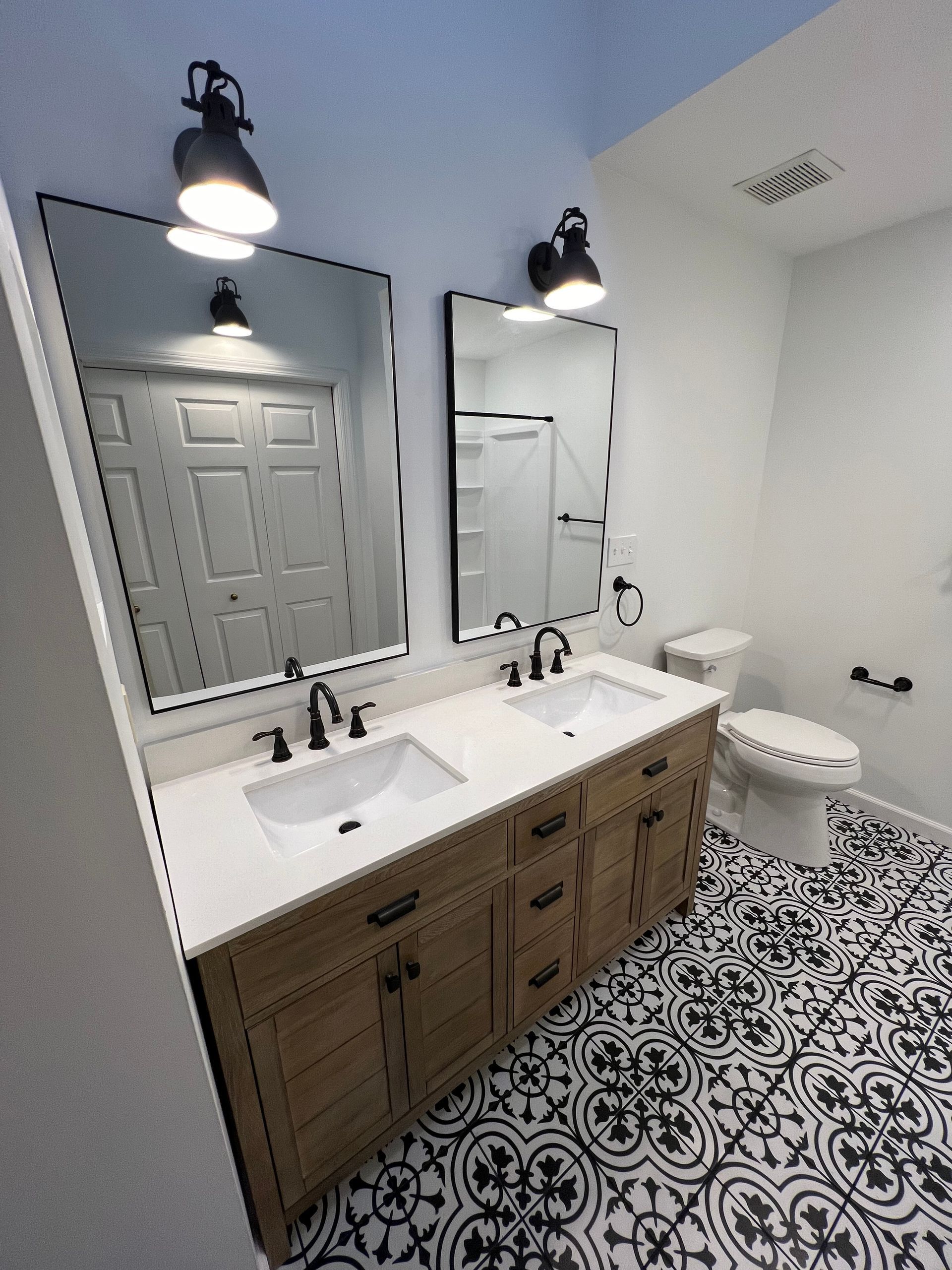 A bathroom with two sinks , a toilet , and two mirrors.