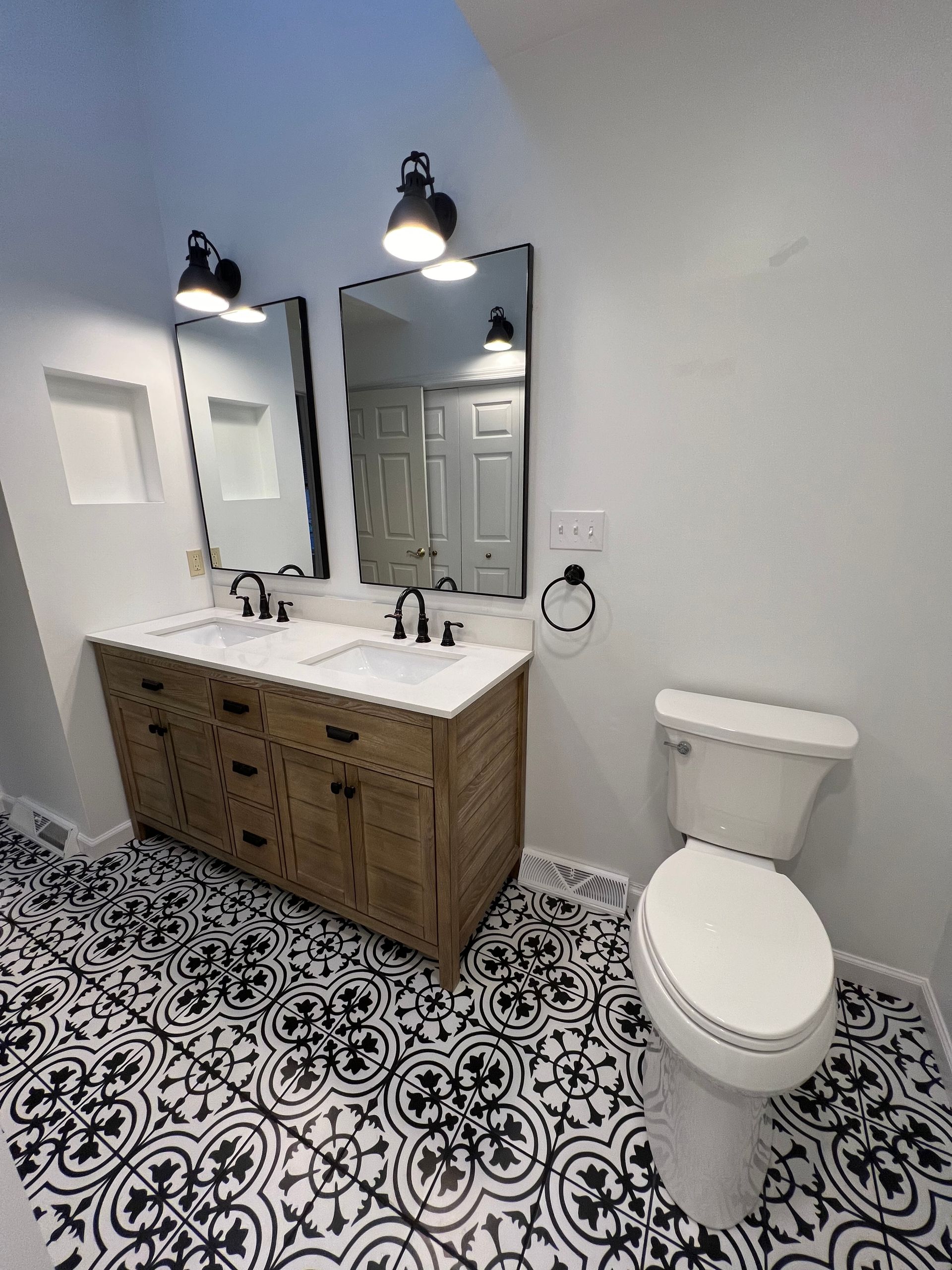 A bathroom with two sinks , a toilet , and two mirrors.