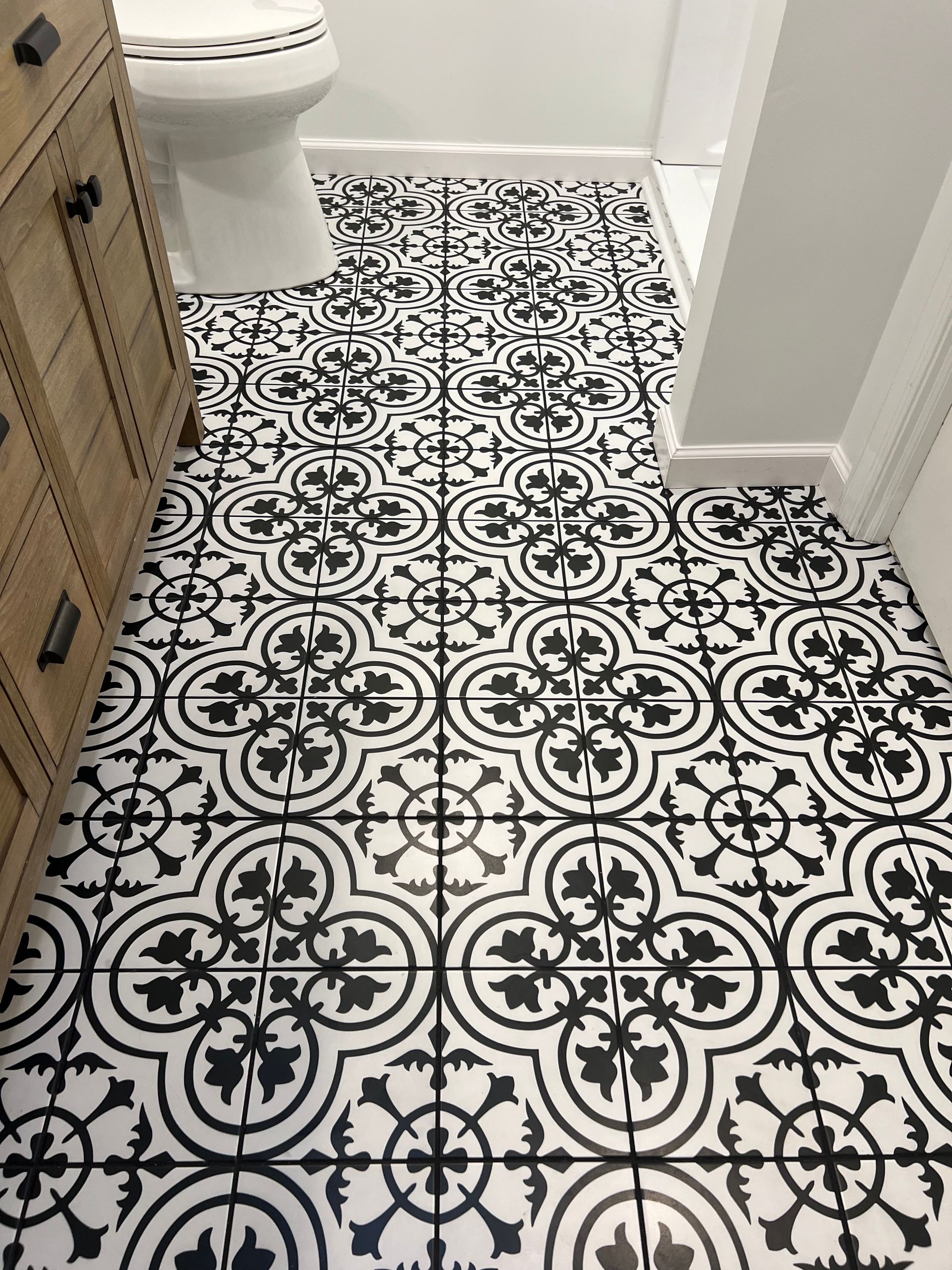 A bathroom with a black and white tile floor and a toilet.