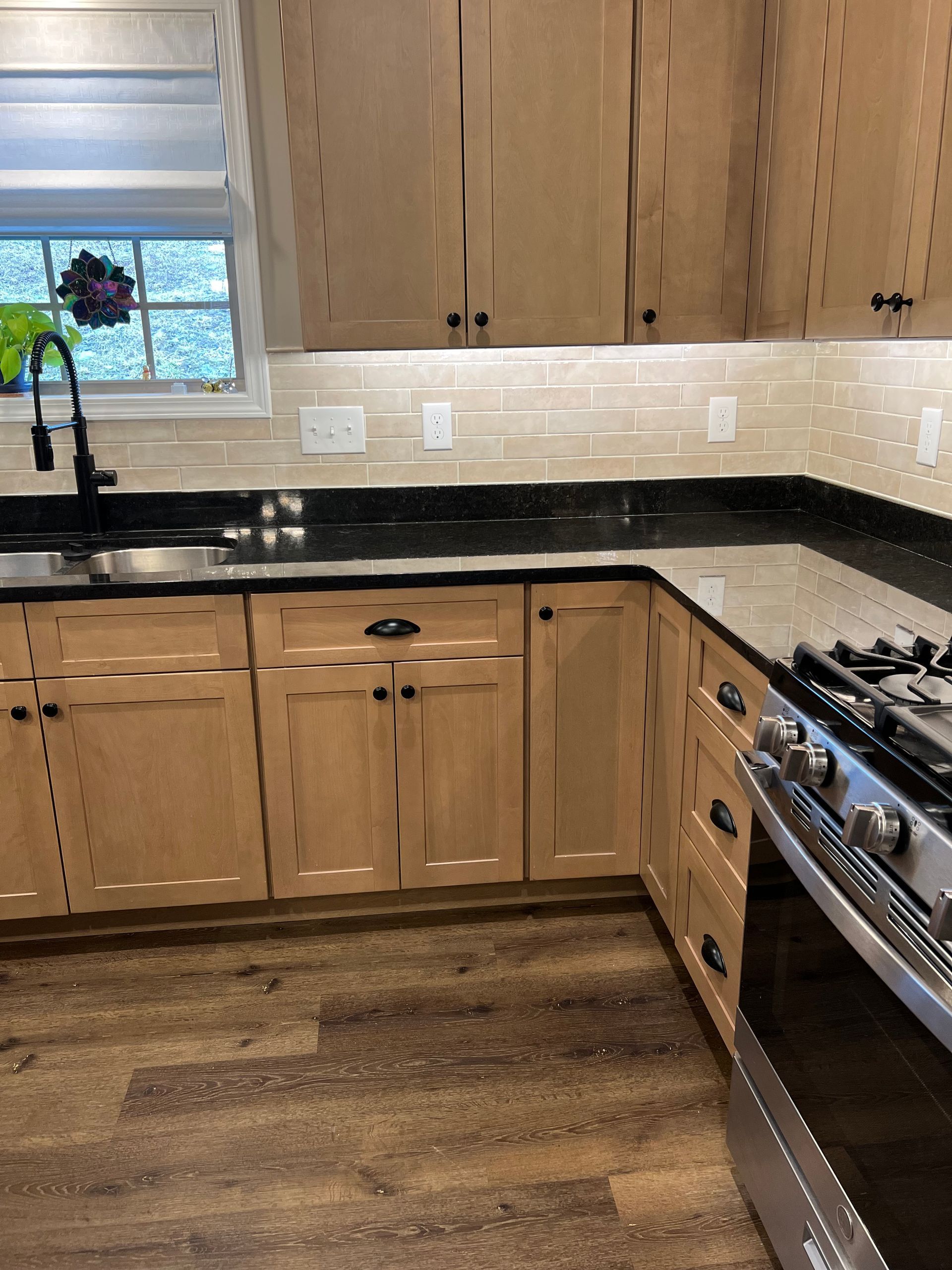 A kitchen with wooden cabinets , a stove , a sink , and a window.