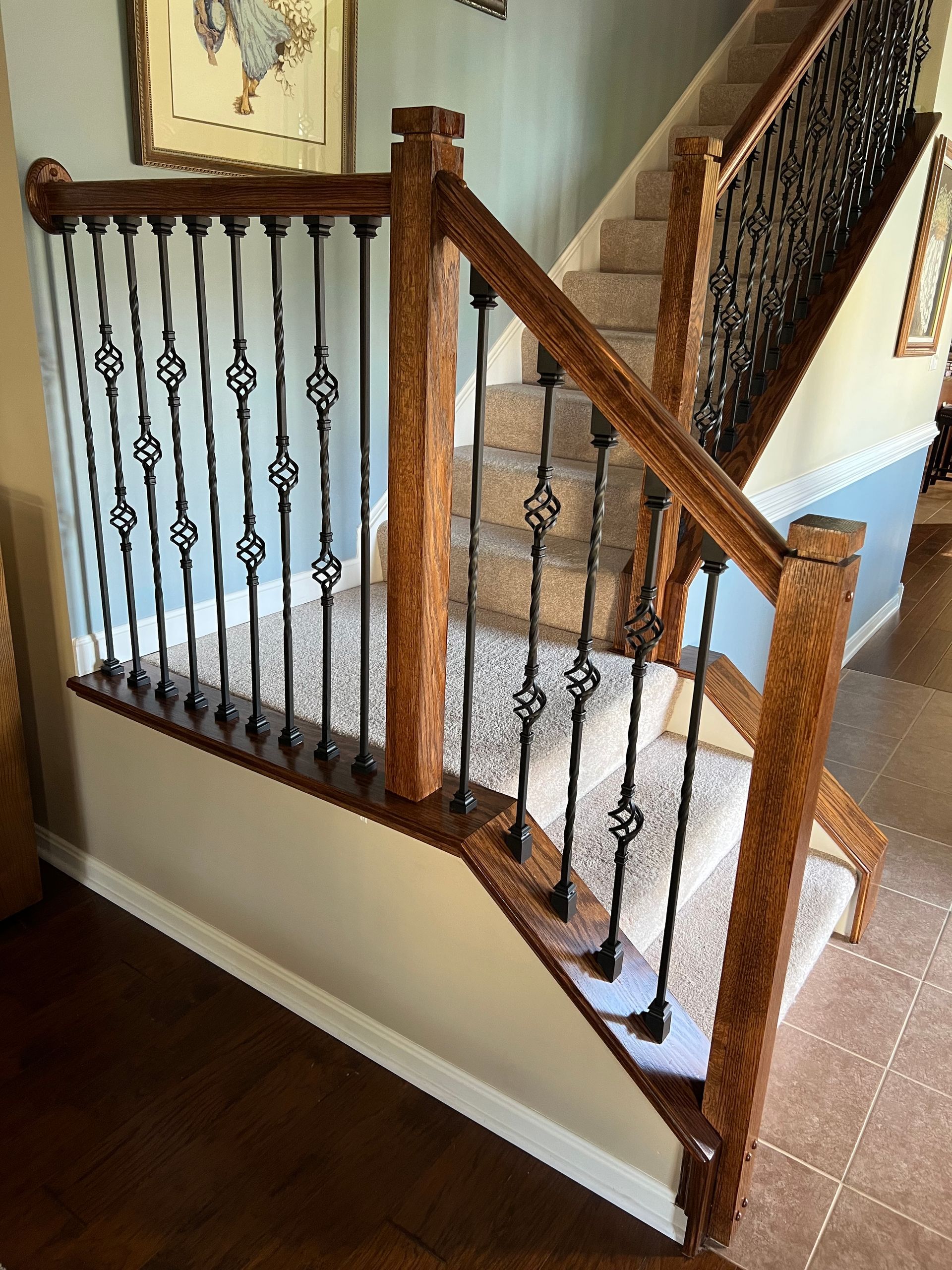 A wooden staircase with a wrought iron railing in a house.