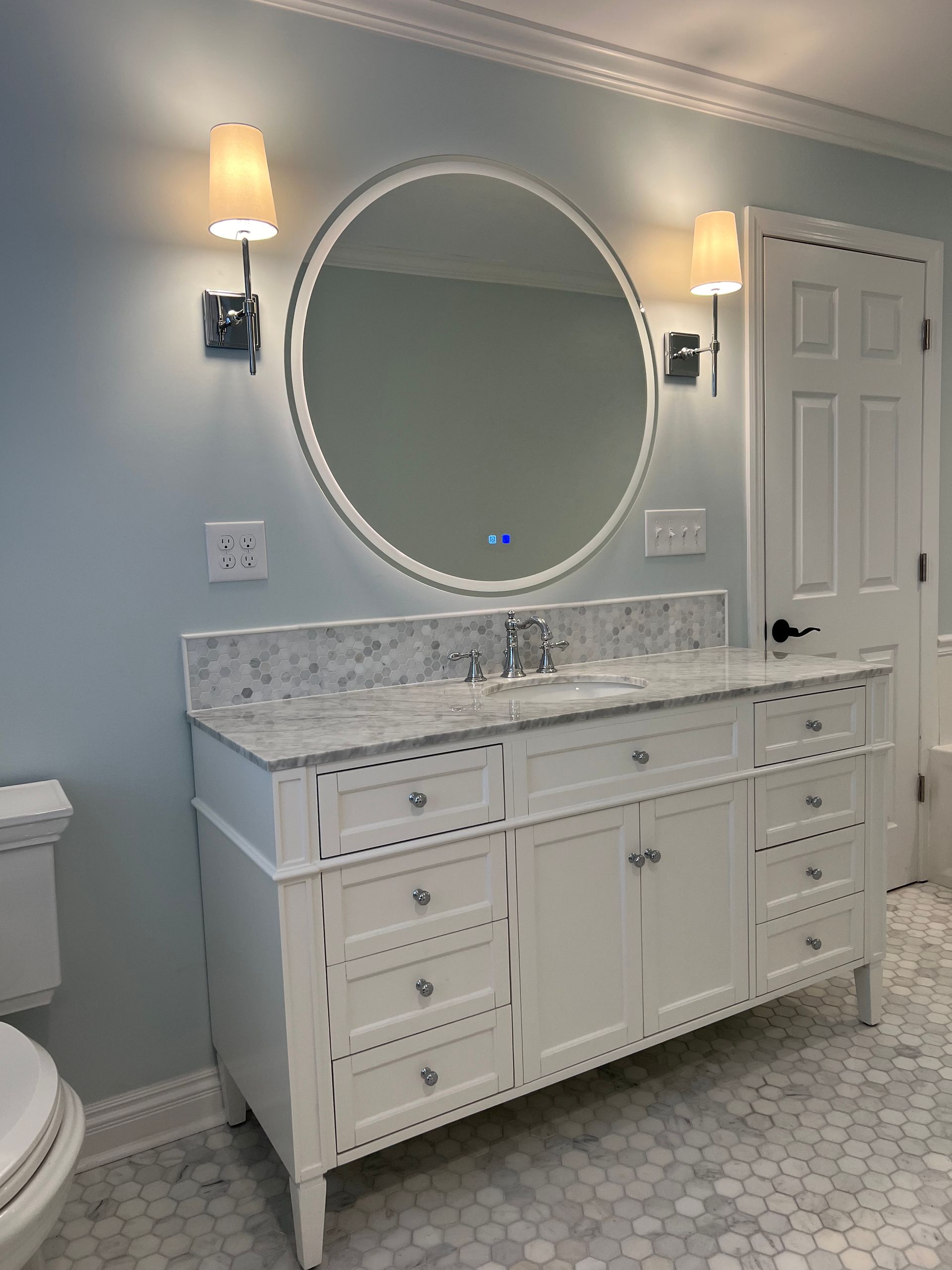 A bathroom with a sink , mirror and toilet.