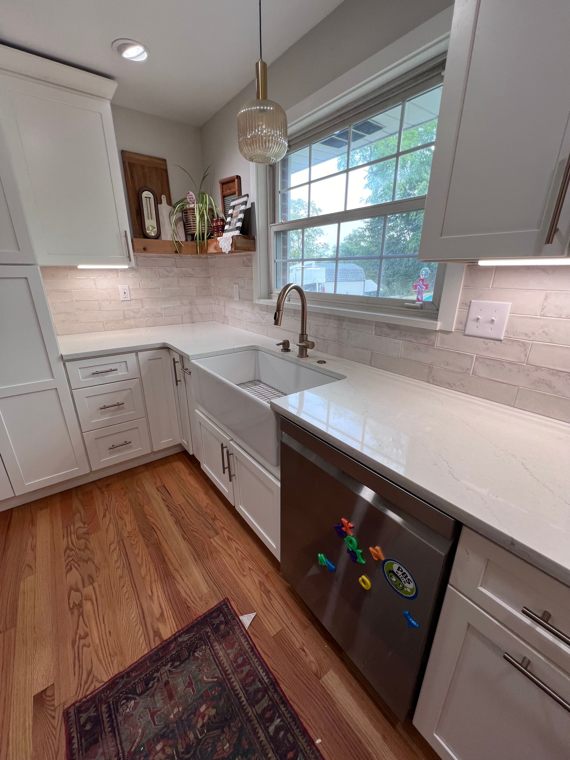 A kitchen with a sink , dishwasher , and window.