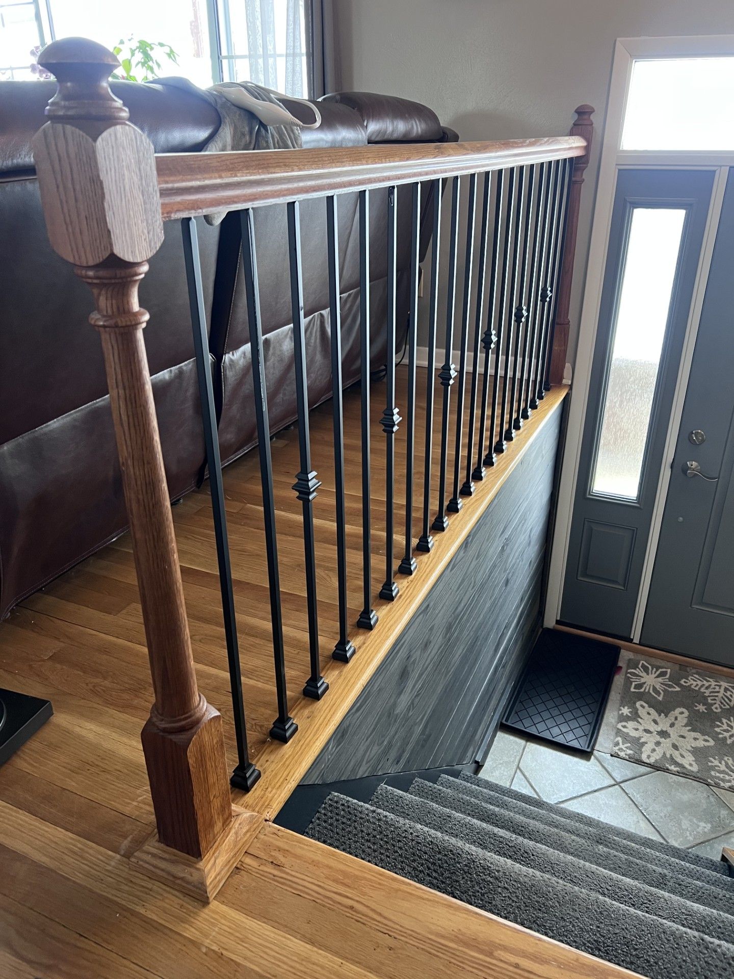 A wooden railing on a set of stairs in a living room next to a door.