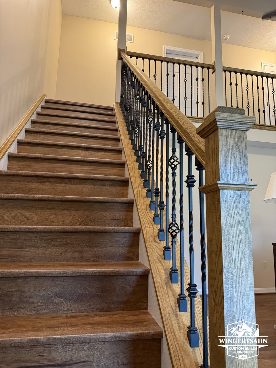 Wooden staircase with black iron railing in a beige home interior