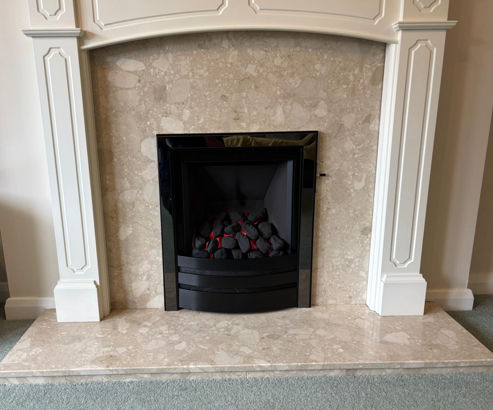 Built-in fireplace with black firebox and beige stone surround, framed by white columns.