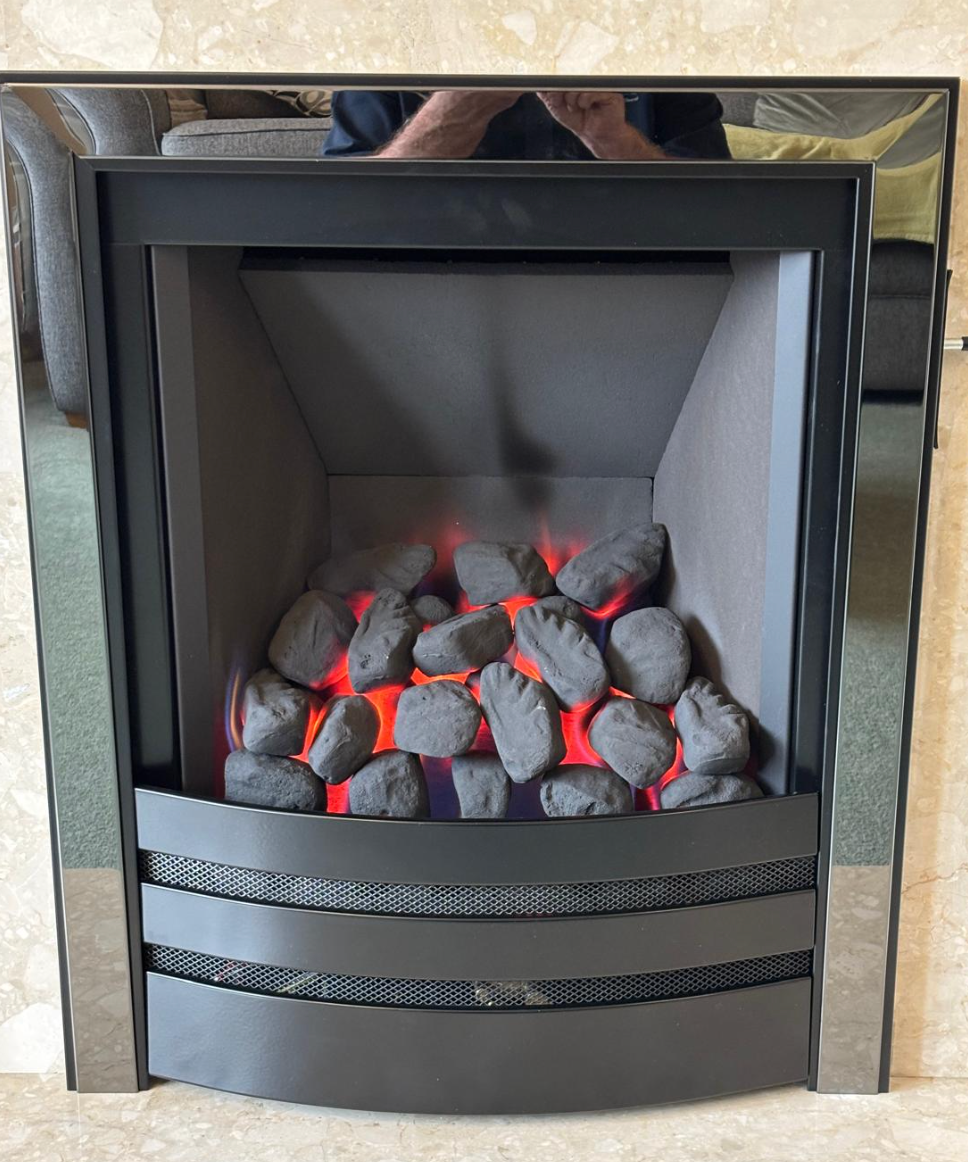 Lit charcoal glowing in a black metal fireplace insert