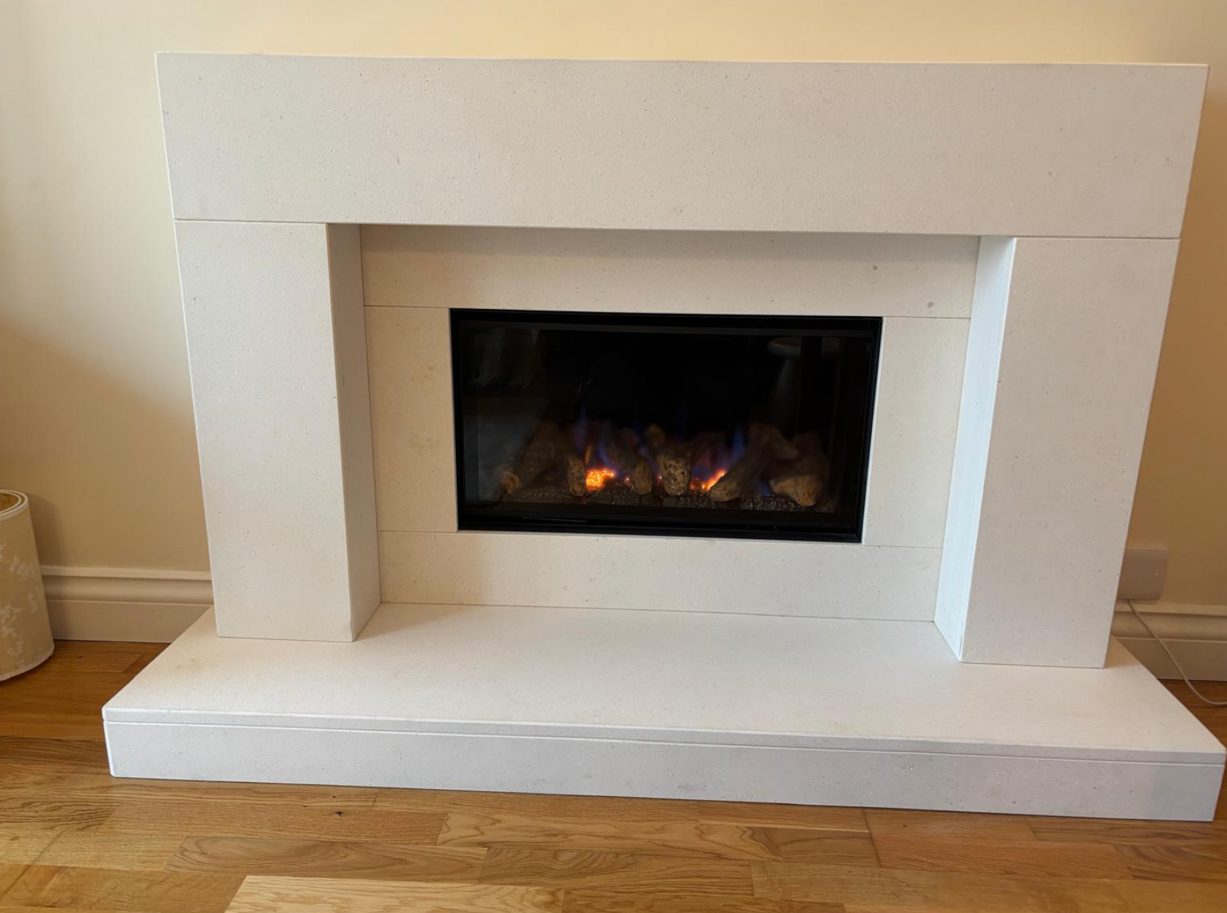 White faux fireplace with a black electric fire insert in a room with wood flooring.