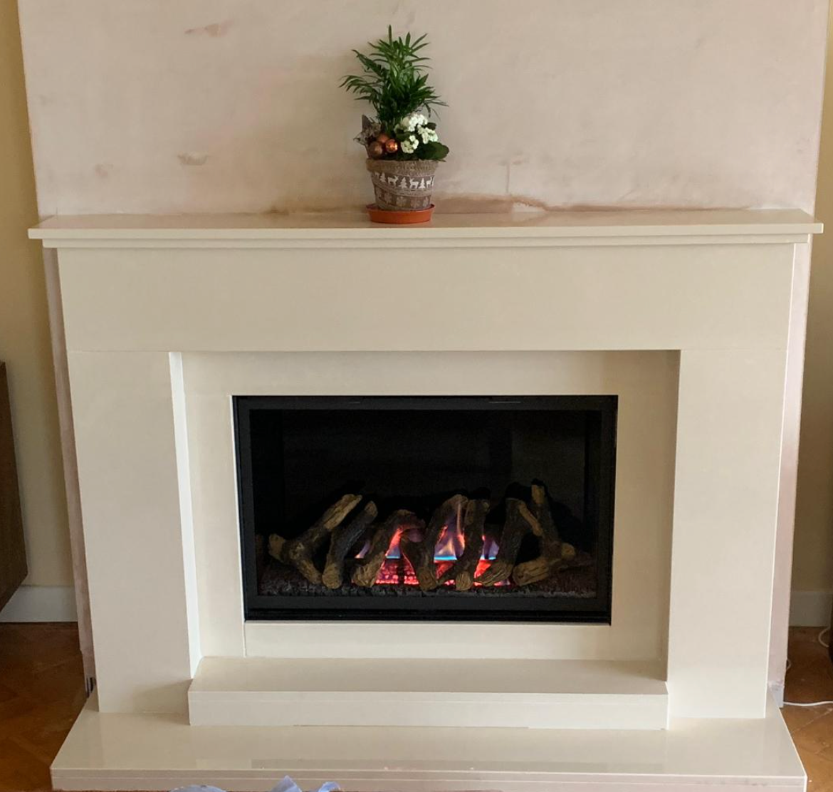 White fireplace mantel with a small potted plant above a lit gas fire