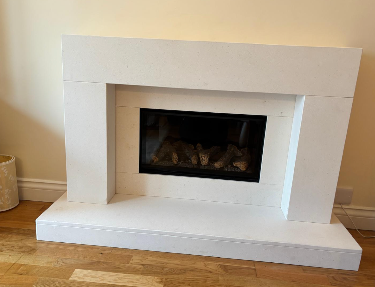 White faux fireplace surround with a dark built-in firebox in a room with wood floor.