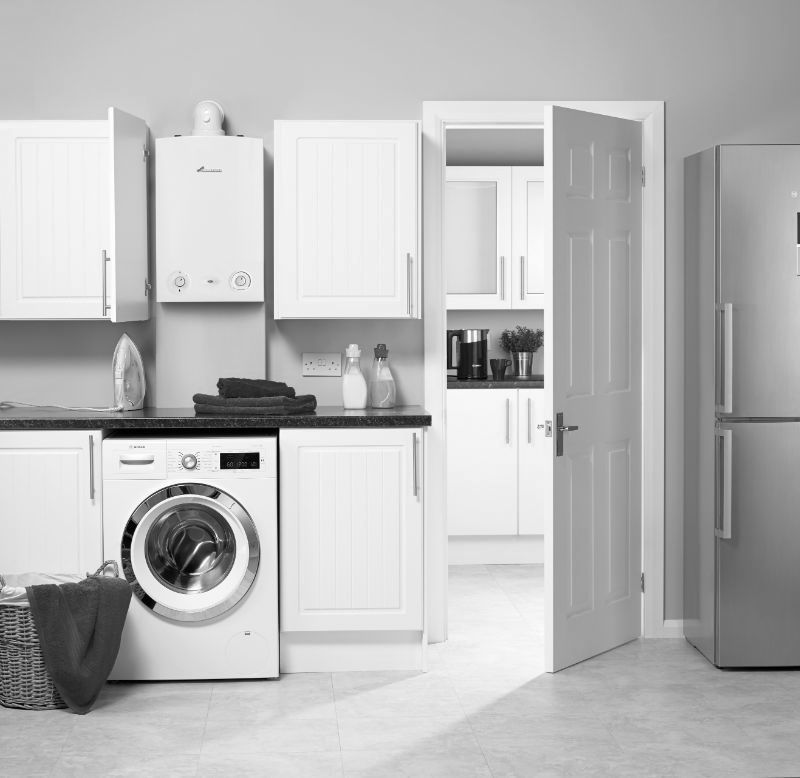 A black and white photo of a kitchen with a washer and dryer