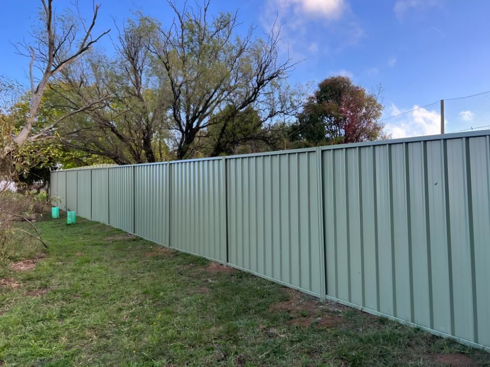 Green Metal Fence in a Yard With Trees and Blue Sky — LD Carpentry in Goulburn, NSW