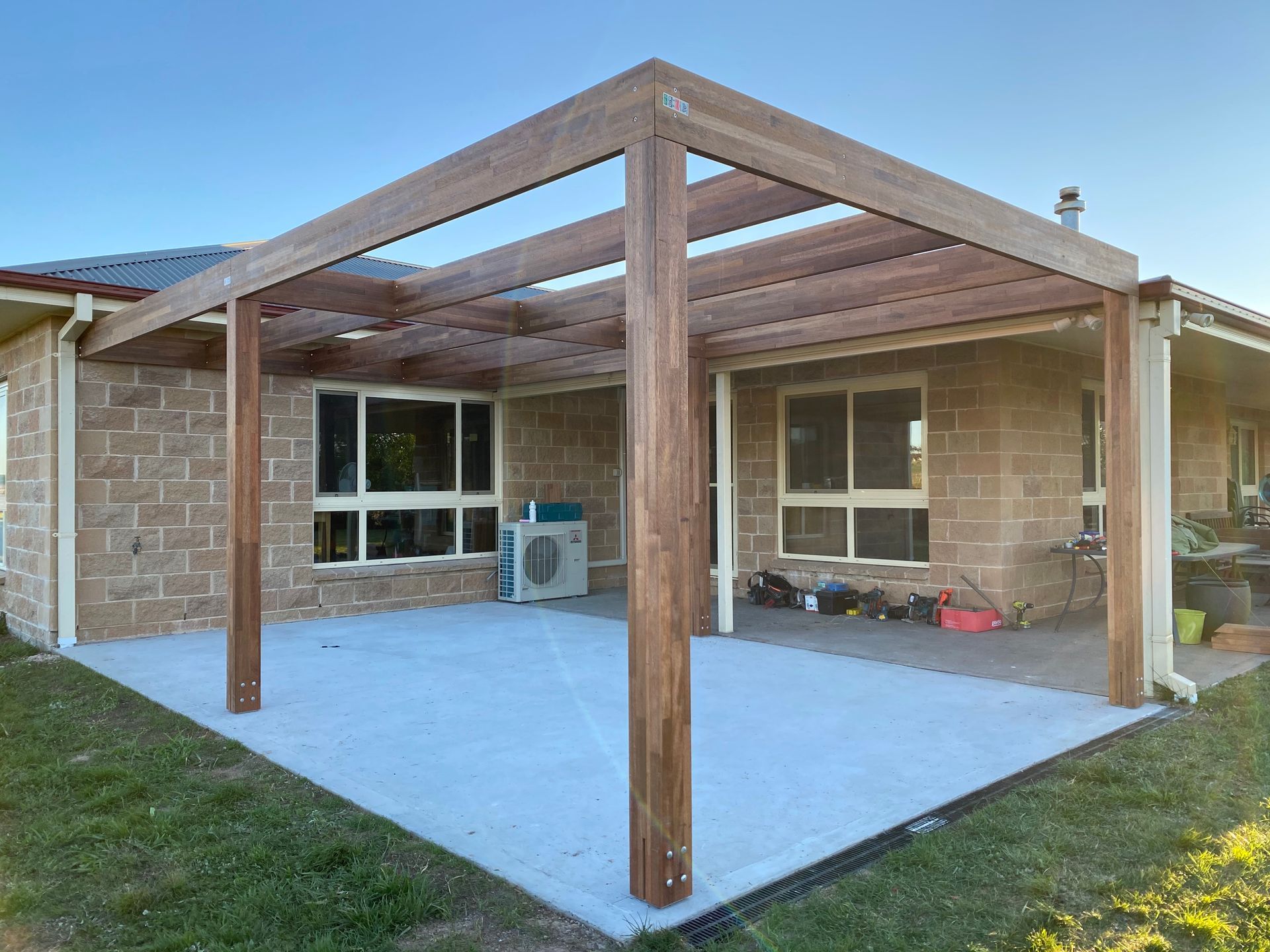 A wooden pergola over a concrete patio attached to a brick home — LD Carpentry in Goulburn, NSW