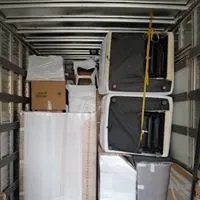 Camion per traslochi carico di mobili impilati, scatole e oggetti coperti all'interno di pareti metalliche.
