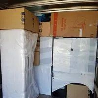 Scatole da trasloco imballate e mobili avvolti e impilati in un deposito.