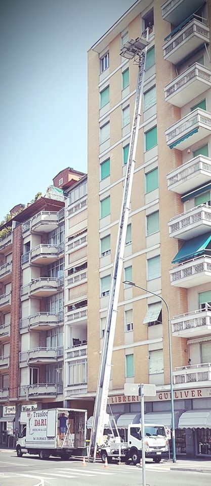Alti palazzi residenziali beige che si affacciano su una strada cittadina, con veicoli parcheggiati al di sotto.