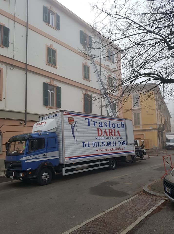Un furgone blu per le consegne è parcheggiato accanto a un condominio in una strada tranquilla.