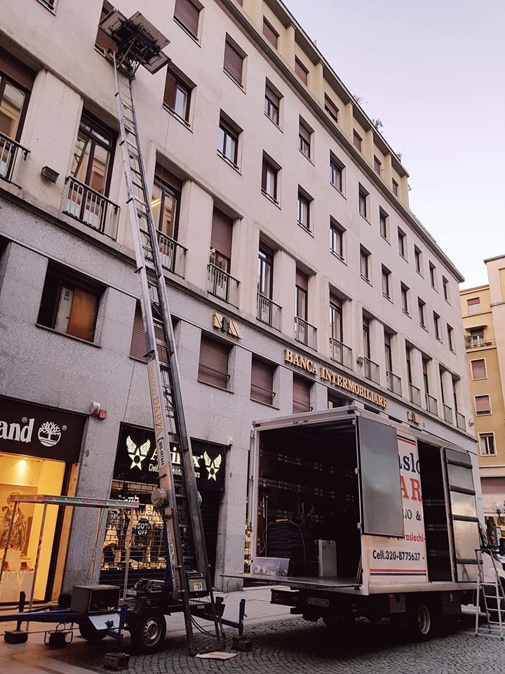 Vista stradale di un condominio bianco con un furgone per le consegne parcheggiato al piano inferiore e una vetrina sulla sinistra.