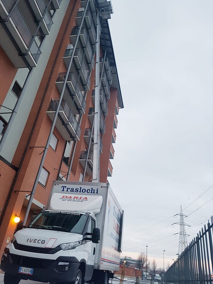 Un camion Tesla bianco parcheggiato accanto a un alto palazzo di mattoni al crepuscolo.